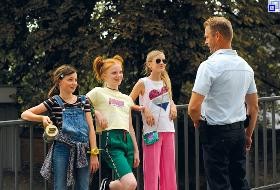 Foto aus dem Film: Drei Mädchen stehen lässig und selbstbewusst vor einem Polizisten