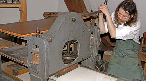 Steindruckmeister Hans Ulrich bedient während einer Vorführung die Lithographie-Presse im J. F. Schreiber-Museum.