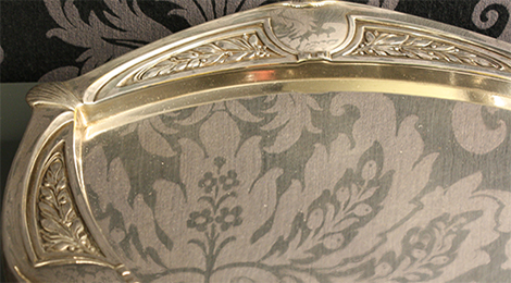 Im sogenannten Silberkabinett: Detailaufnahme eines kleinen versilberten Metalltabletts, dessen Rand mit zurückhaltenden Jugendstilformen geschmückt ist.