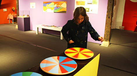 In der Ausstellung: Ein Junge dreht Scheiben mit farbigen Streifen.