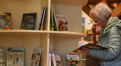 Eine Besucherin betrachtet ein Pop-up-Buch vor einem Regal voller Bücher.